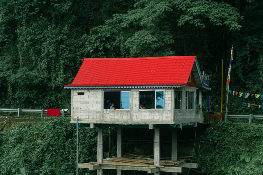 A picturesque house with a red roof nestled in the lush forest of Darjeeling, West Bengal, India.